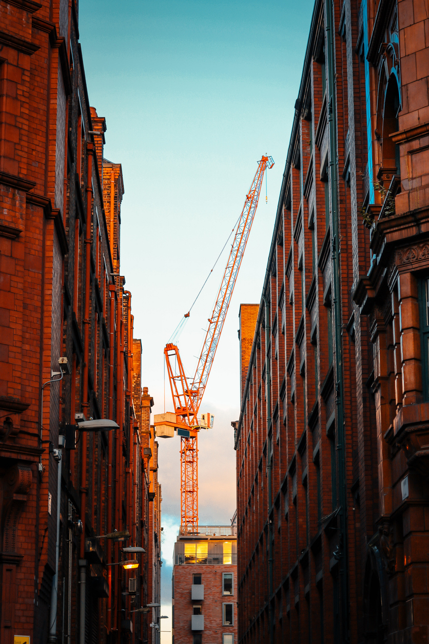 Crane surrounded buy buildings.